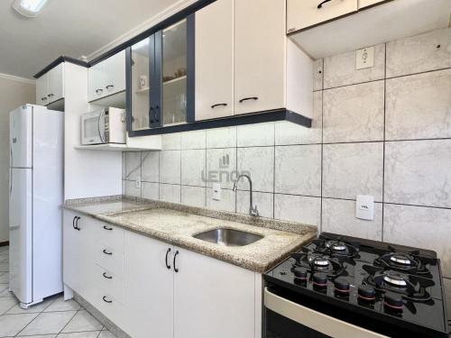 cocina blanca con fregadero y fogones en 205 - Apartamento 02 dormitórios apenas 50m praia de Bombas, en Bombinhas