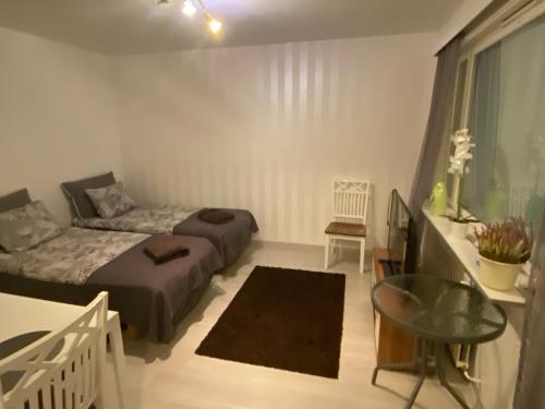 1 dormitorio con 2 camas, mesa y ventana en Koskentien yksiö en Jämsä