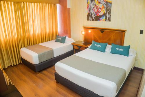 una camera d'albergo con 2 letti e una scrivania di Ayenda Imperio Real a Pereira