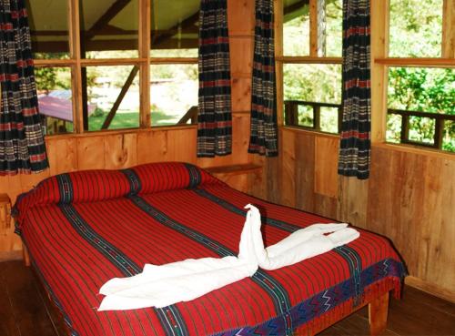 1 dormitorio con 1 cama con sábanas blancas y ventanas en Finca Terra Viva, en Monteverde