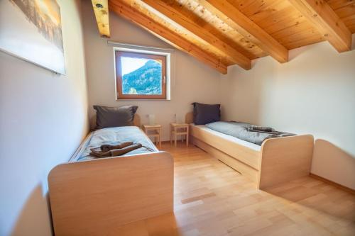 - 2 lits dans une chambre dotée de parquet et d'une fenêtre dans l'établissement Appartement Alpenliebe, à Bichlbach