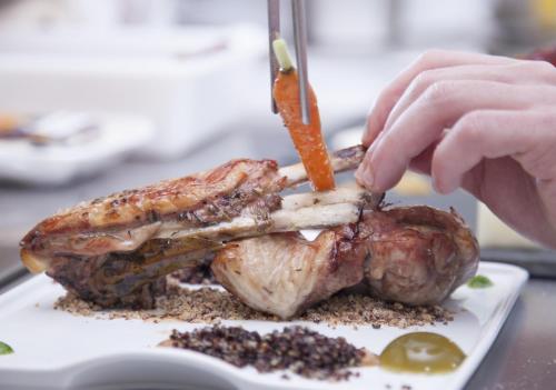 a person cutting a piece of meat on a plate at Hotel Miba in Salobreña