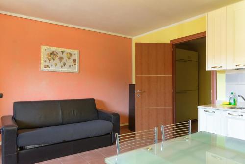 a living room with a black couch and a kitchen at Capanna in Prato Nevoso