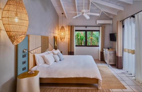 Un dormitorio con una gran cama blanca y una ventana en Cala Luna Boutique Hotel & Villas, en Tamarindo
