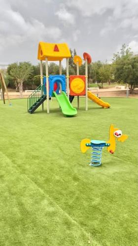 a playground with slides and play equipment in a park at Superbe Appartement avec Piscine - 5 min de la Plage à Imi Ouaddar in Imi Ouaddar