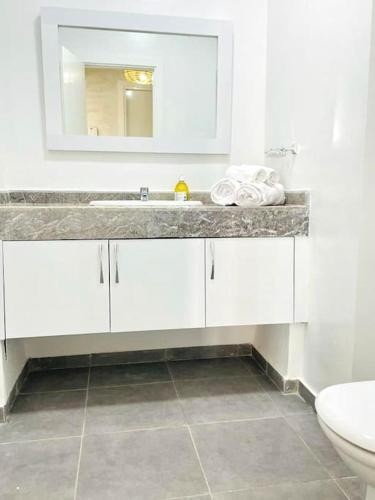 a white bathroom with a sink and a toilet at Superbe Appartement avec Piscine - 5 min de la Plage à Imi Ouaddar in Imi Ouaddar