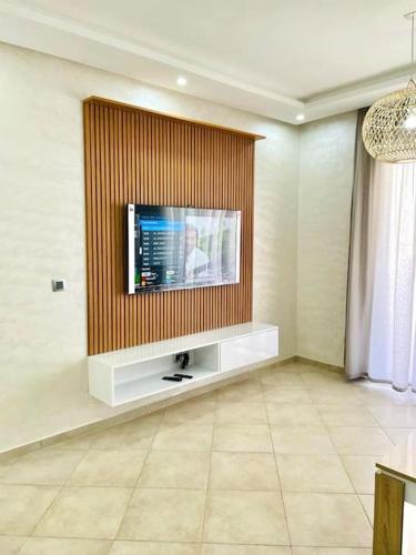 a living room with a flat screen tv on a wall at Superbe Appartement avec Piscine - 5 min de la Plage à Imi Ouaddar in Imi Ouaddar