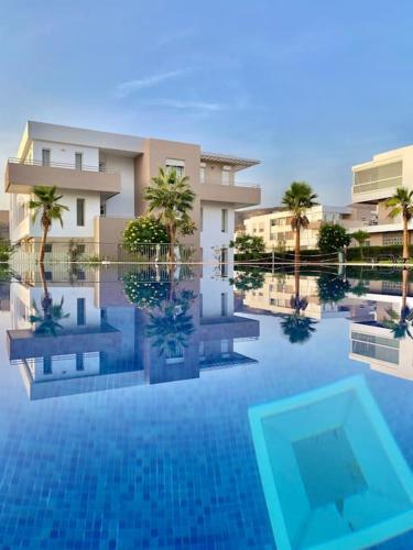 a rendering of a swimming pool with palm trees and buildings at Superbe Appartement avec Piscine - 5 min de la Plage à Imi Ouaddar in Imi Ouaddar