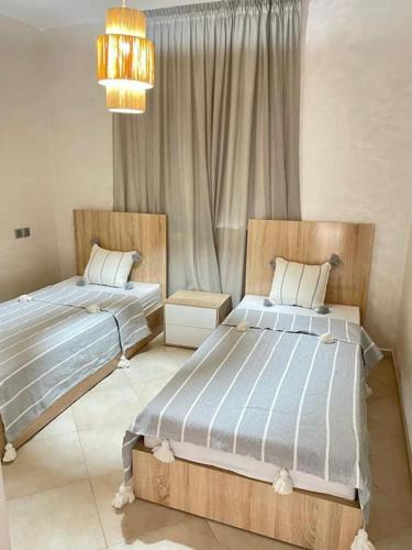a bedroom with two beds and a chandelier at Superbe Appartement avec Piscine - 5 min de la Plage à Imi Ouaddar in Imi Ouaddar