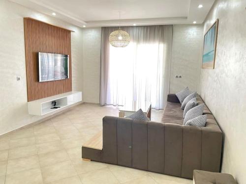 a living room with a couch and a tv at Superbe Appartement avec Piscine - 5 min de la Plage à Imi Ouaddar in Imi Ouaddar