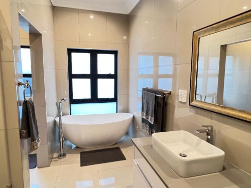 ein Badezimmer mit einer großen weißen Badewanne und einem Waschbecken in der Unterkunft Sasavona Cottage - 349 Vaal de Grace Golf Estate in Parys