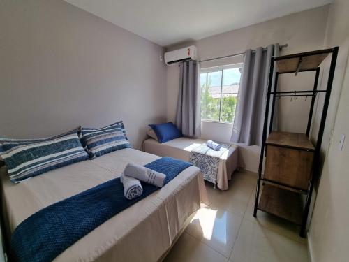 1 dormitorio con cama y ventana en Curta Praia de Armação - Casa Violeta, en Penha