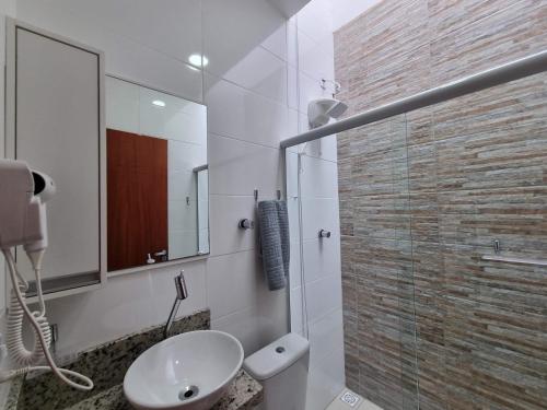 a white bathroom with a sink and a mirror at Curta Praia de Armação - Casa Violeta in Penha