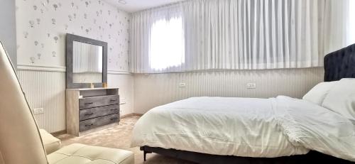 a bedroom with a bed and a mirror and a chair at Mina Akko sea view in ‘Akko