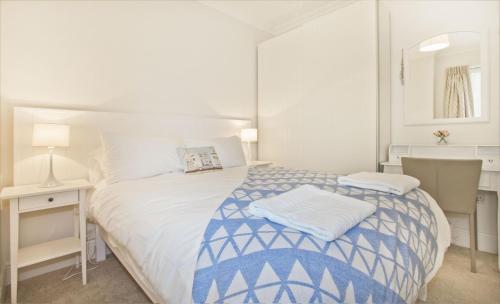 a white bedroom with a blue and white bed and a desk at Beautiful Aberdovey Seafront Apartment 2 in Aberdyfi