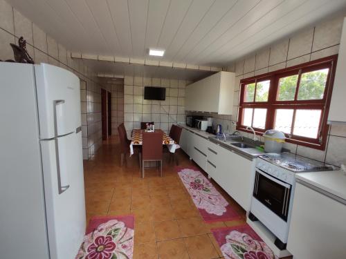 a kitchen with a table and a white refrigerator at Casa aconchegante a 4km-5min da Guarda do Embaú in Guarda do Embaú