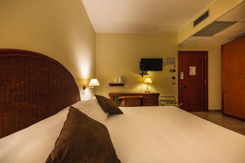 a bedroom with a large bed and a television at Apulia Hotel Taranto Ara Solis in Lido Azzurro