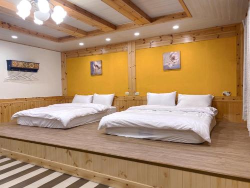 two beds in a room with a yellow wall at 薔薇谷 民宿字108號 in Fuxing