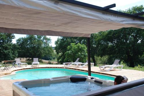 bañera de hidromasaje con sombrilla junto a la piscina en les bulles perchées de lartigue, en Margouët-Meymès