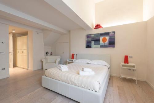 een witte slaapkamer met een groot wit bed met witte lakens bij Le Grazie Luxury Apartment in Florence