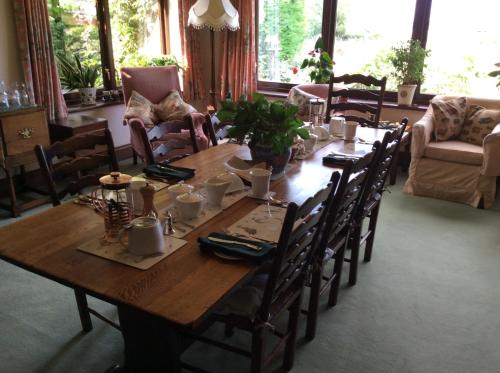 una mesa de madera en una sala de estar con sillas y una sidra de mesa en NIGHTINGALE B&B en Pershore