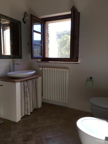 baño con lavabo y aseo y 2 ventanas en Casa Batano, en San Casciano dei Bagni