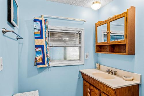 een blauwe badkamer met een wastafel en een raam bij Fanci's Hideout in Atlantic Beach