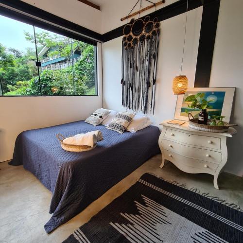 a bedroom with a bed and a dresser and a window at Vila Bambu Ilhabela, Santa Tereza in Ilhabela