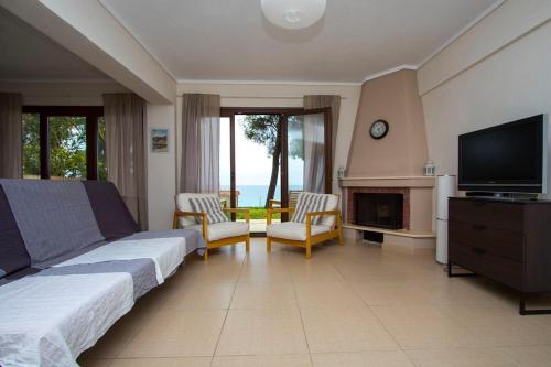 a living room with a bed and a television at Beachfront Villa Possidi by Halkidiki Villas in Possidi