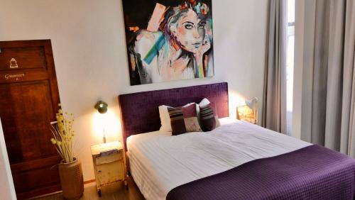a bedroom with a purple bed with a painting on the wall at BE41 Boutique Hotel in Maastricht
