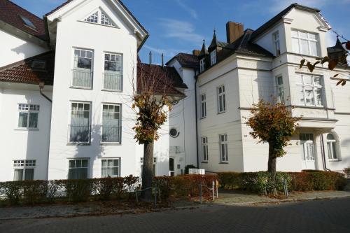 un gran edificio blanco con árboles delante de él en Schloss Hohenzollern - Wohnung 03, en Ahlbeck