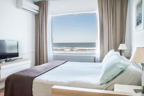 a bedroom with a bed and a window with the ocean at Pinamar Beach Resort in Pinamar