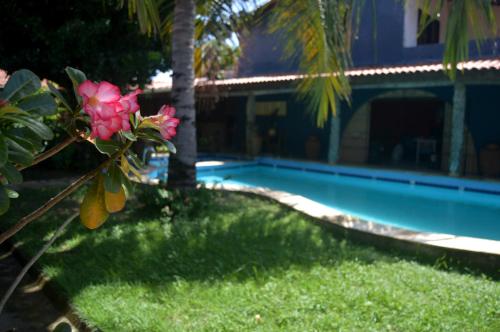 a yard with a swimming pool and a pink flower at Pousada La Luna in Paracuru