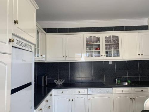 a white kitchen with white cabinets and black tiles at Centro da cidade Amarante in Amarante