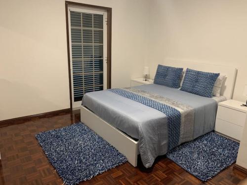 a bedroom with a bed with blue pillows and a window at Centro da cidade Amarante in Amarante