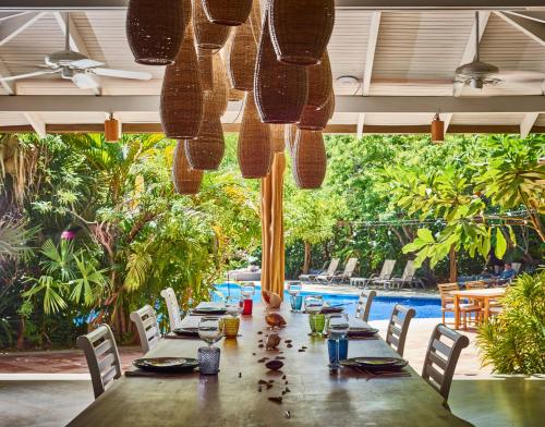 a long table in a restaurant with a pool at Cala Luna Boutique Hotel & Villas in Tamarindo