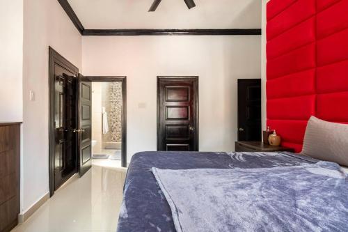 a bedroom with a bed with a red headboard at Brand New Pool Manor Park with WIFI centrally-located in Kingston