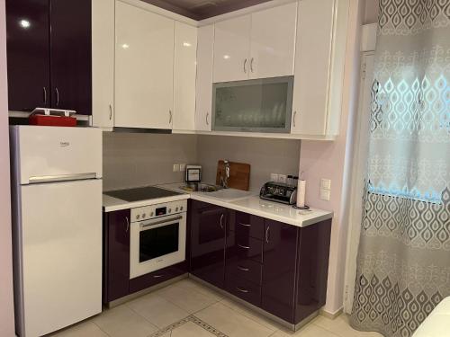 a kitchen with white cabinets and a white refrigerator at Piraeus Cozy in Piraeus