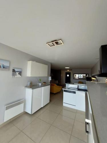 une grande cuisine avec des armoires et des appareils blancs dans l'établissement La Cabane au Sud ~300 m de l'Océan, à Mimizan