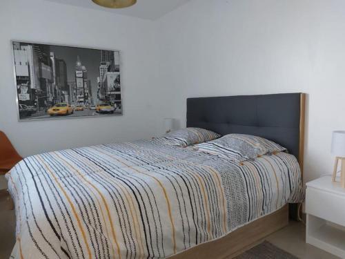 une chambre avec un lit avec un tableau sur le mur dans l'établissement La Cabane au Sud ~300 m de l'Océan, à Mimizan