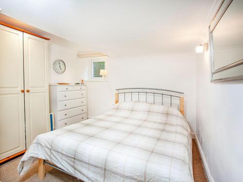 a white bedroom with a bed and a dresser at Westerlands Apartment in Torquay
