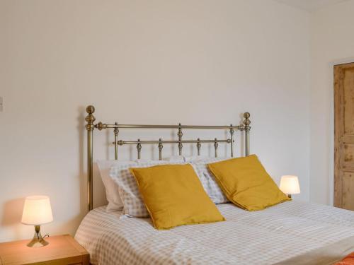 1 dormitorio con 1 cama con 2 almohadas amarillas en Fox Cottage, en Beverley