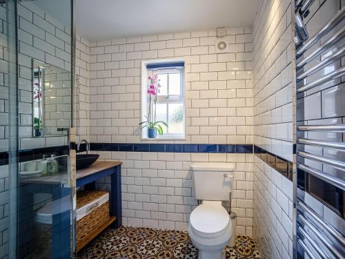 a bathroom with a toilet and a sink and a window at Farmside Cottage-uk35018 in Chatton