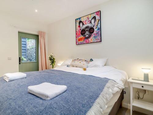 a bedroom with a blue and white bed and a painting at Church Garden Cottage in Higham