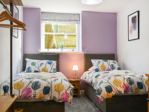 two beds in a room with purple walls and a window at No1 Park Lodge in Buxton