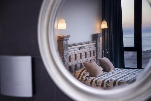 a mirror reflecting a bed in a room with a window at Hotel Miba in Salobreña