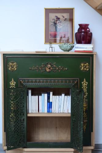 a green book shelf with books on it at Au four et au jardin in Namur