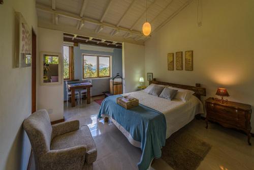 a bedroom with a bed and a chair and a desk at Pousada Mandala das Águas in Aiuruoca