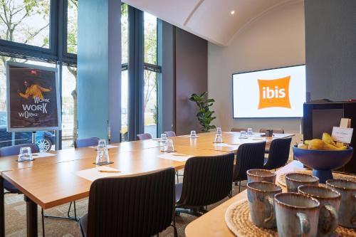 a conference room with tables and chairs and a big screen at ibis Paris La Villette Cité des Sciences 19ème in Paris