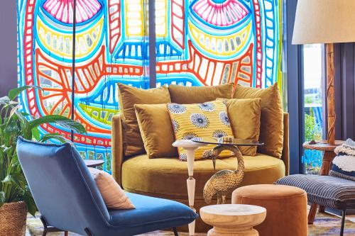 a living room with a couch and a colorful wall at ibis Paris La Villette Cité des Sciences 19ème in Paris